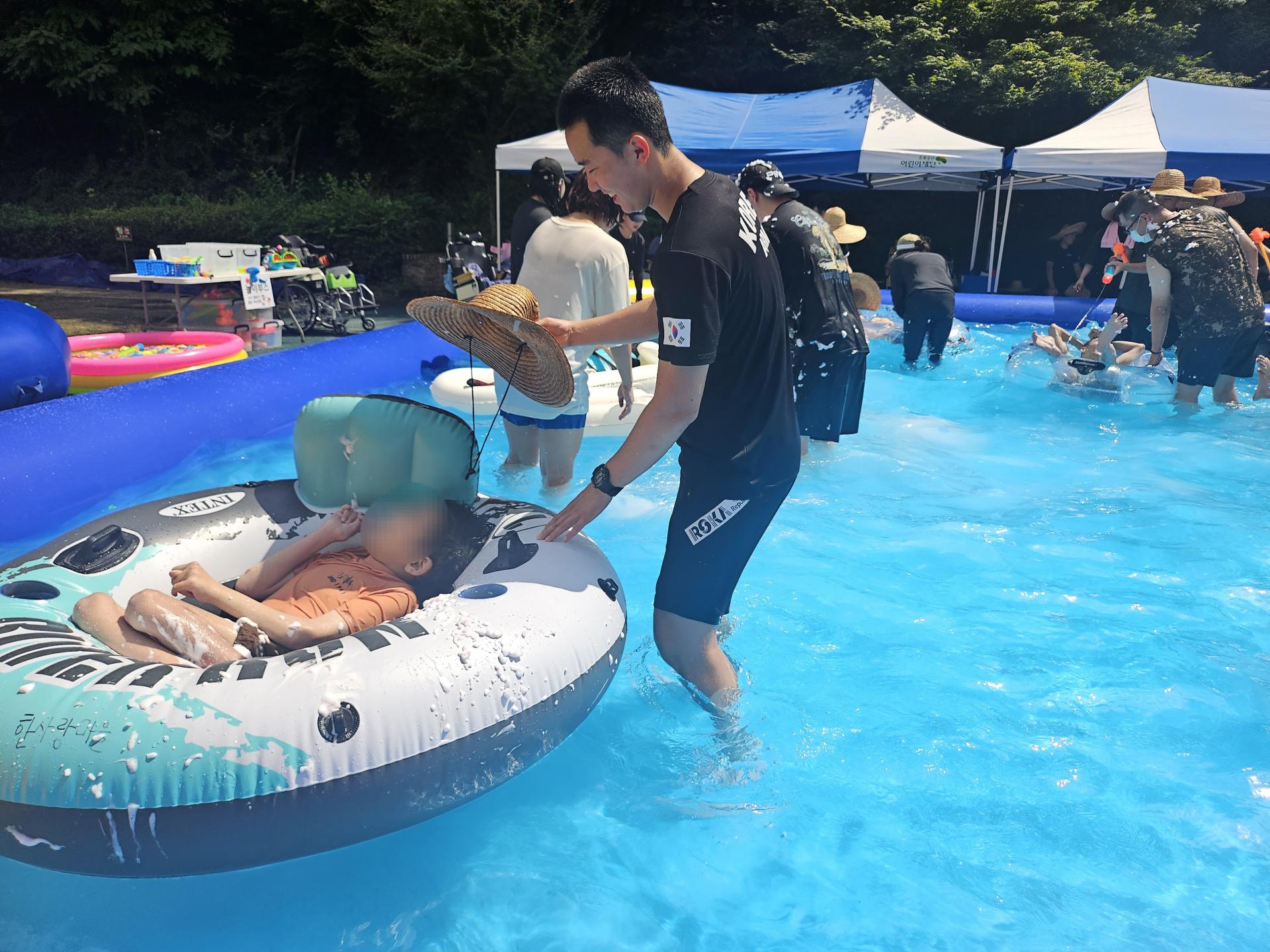 튜브를 탄 이용자와 모자를 이용해 햇빛을 막아주는 자원봉사자