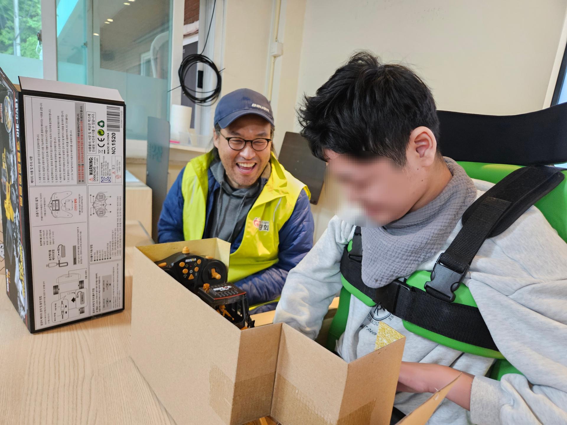 함께 선물을 열어보며 즐거워하는 이용자와 봉사자