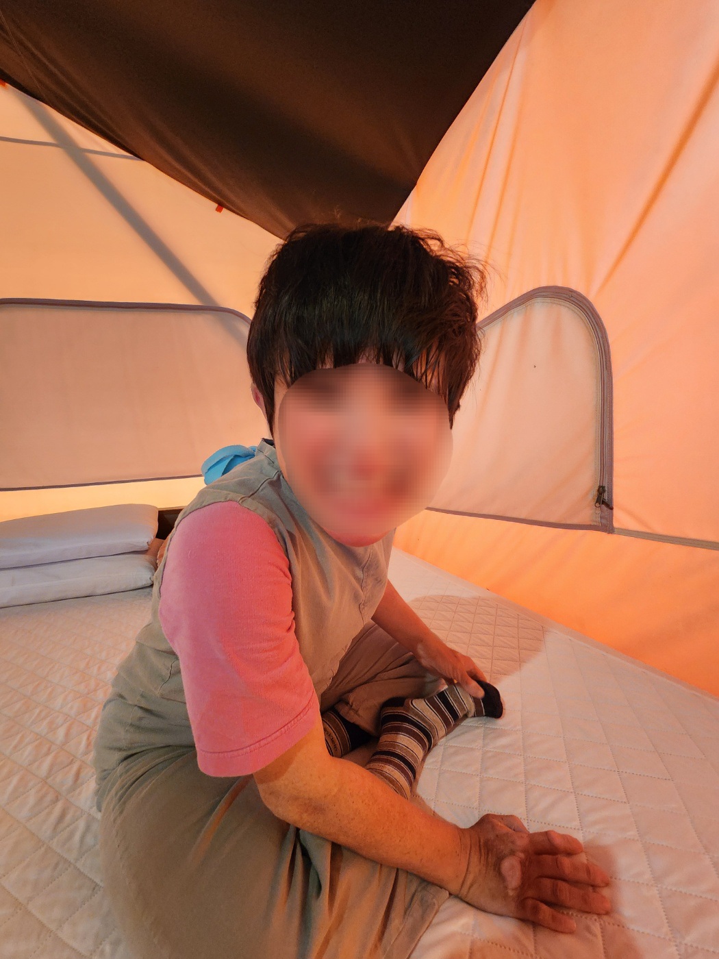 캠핑장 안 침대위에 앉아서 웃는 이용자