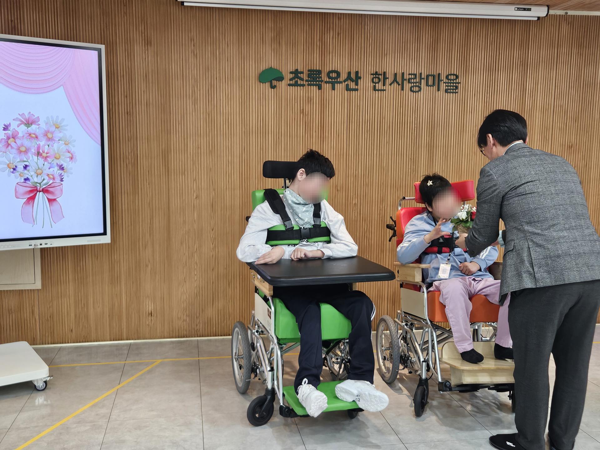 위원증과 꽃바구니를 받는 이용자와 전달하는 원장님