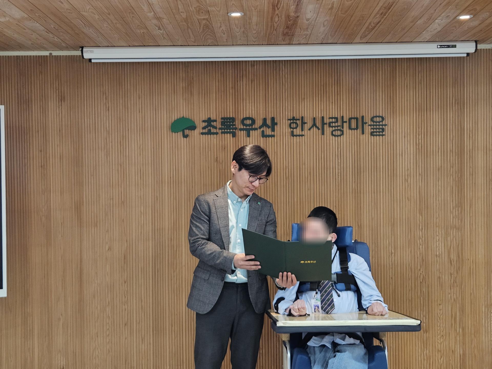 임명장을 함께 바라보는 원장님과 이용자