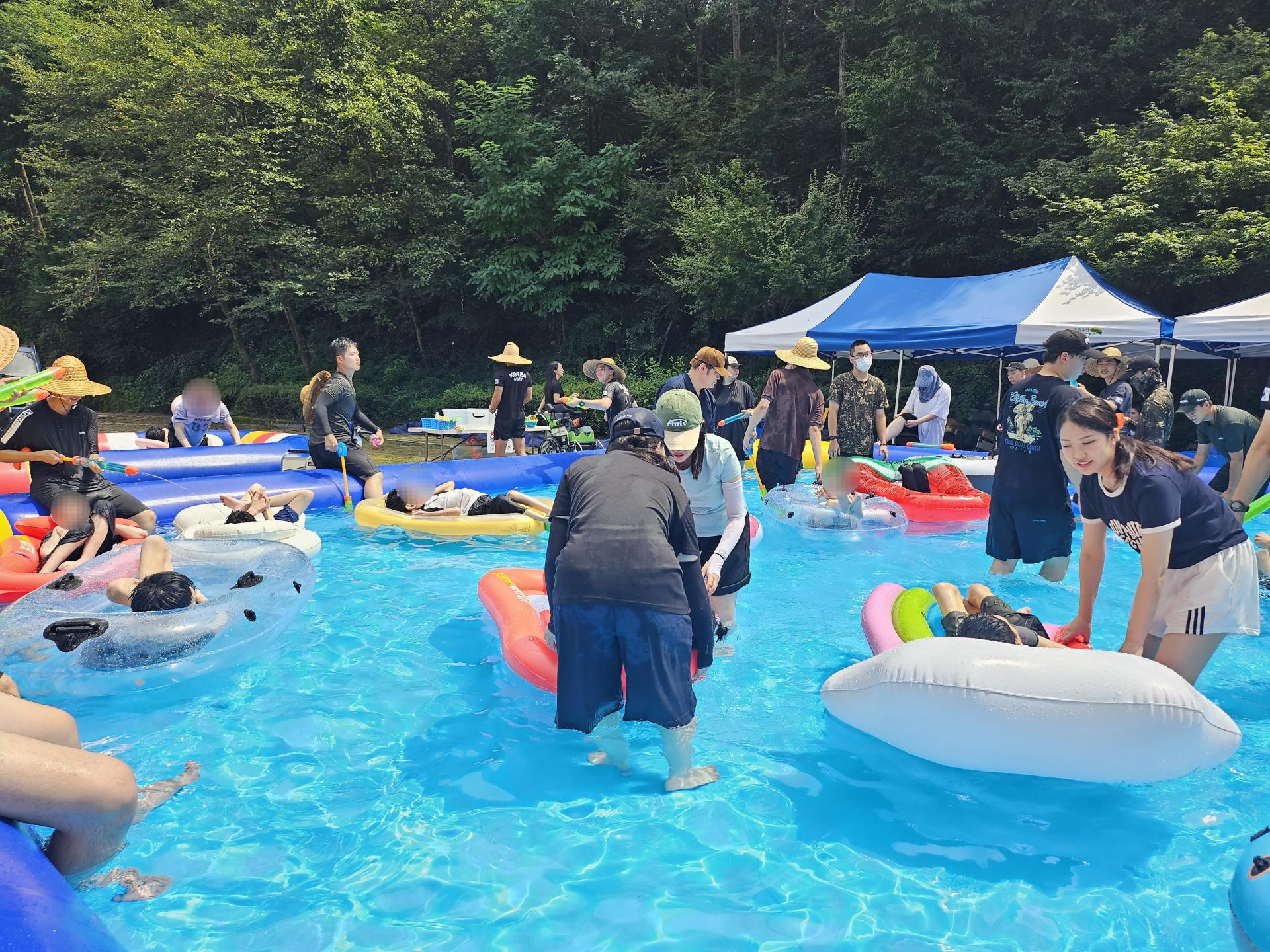 튜브를 탄 이용자가 물놀이를 즐길수 있게 함께하는 자원봉사자들