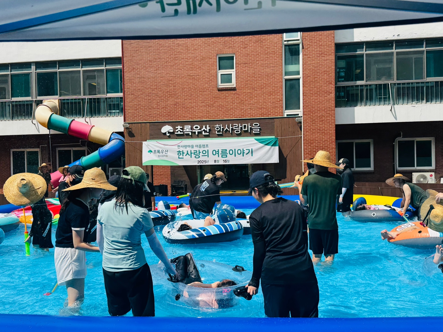 튜브를 탄 이용자가 물놀이를 즐길수 있게 함께하는 자원봉사자들