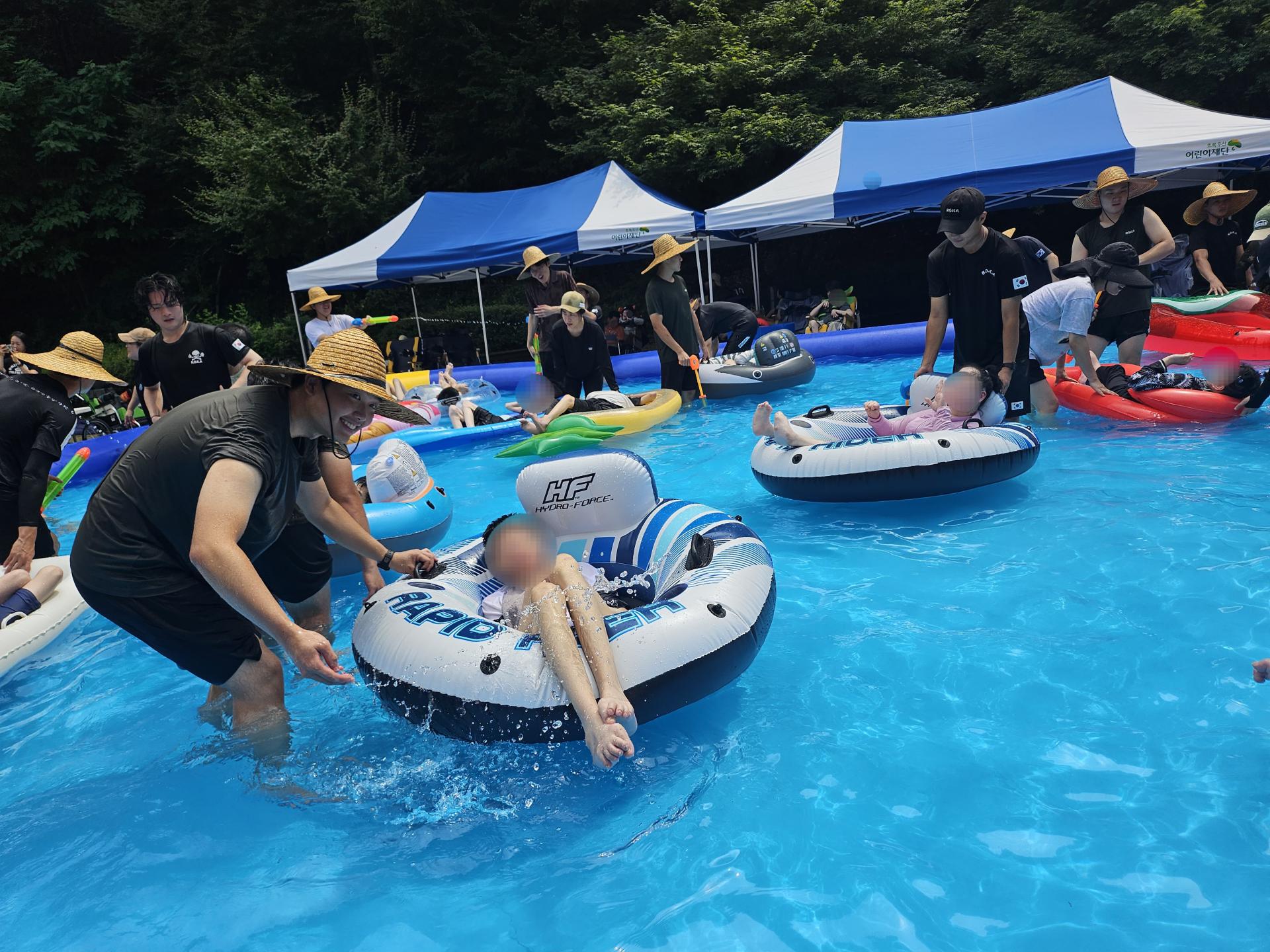 튜브를 탄 이용자가 물놀이를 즐길수 있게 함께하는 자원봉사자들