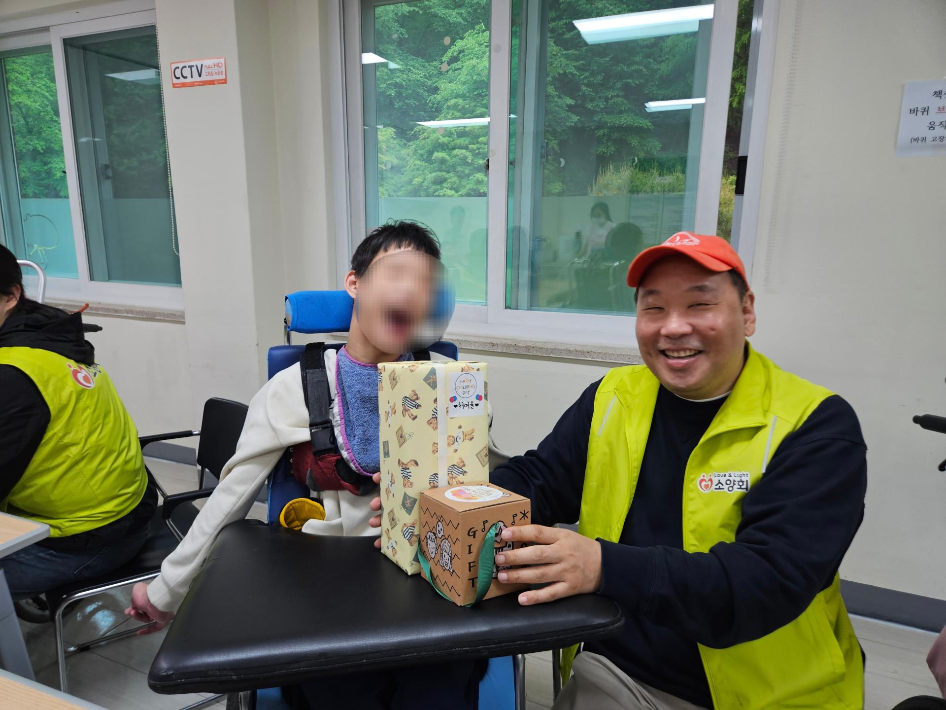 선물을 받아 즐거워하는 이용자와 함께 웃는 봉사자