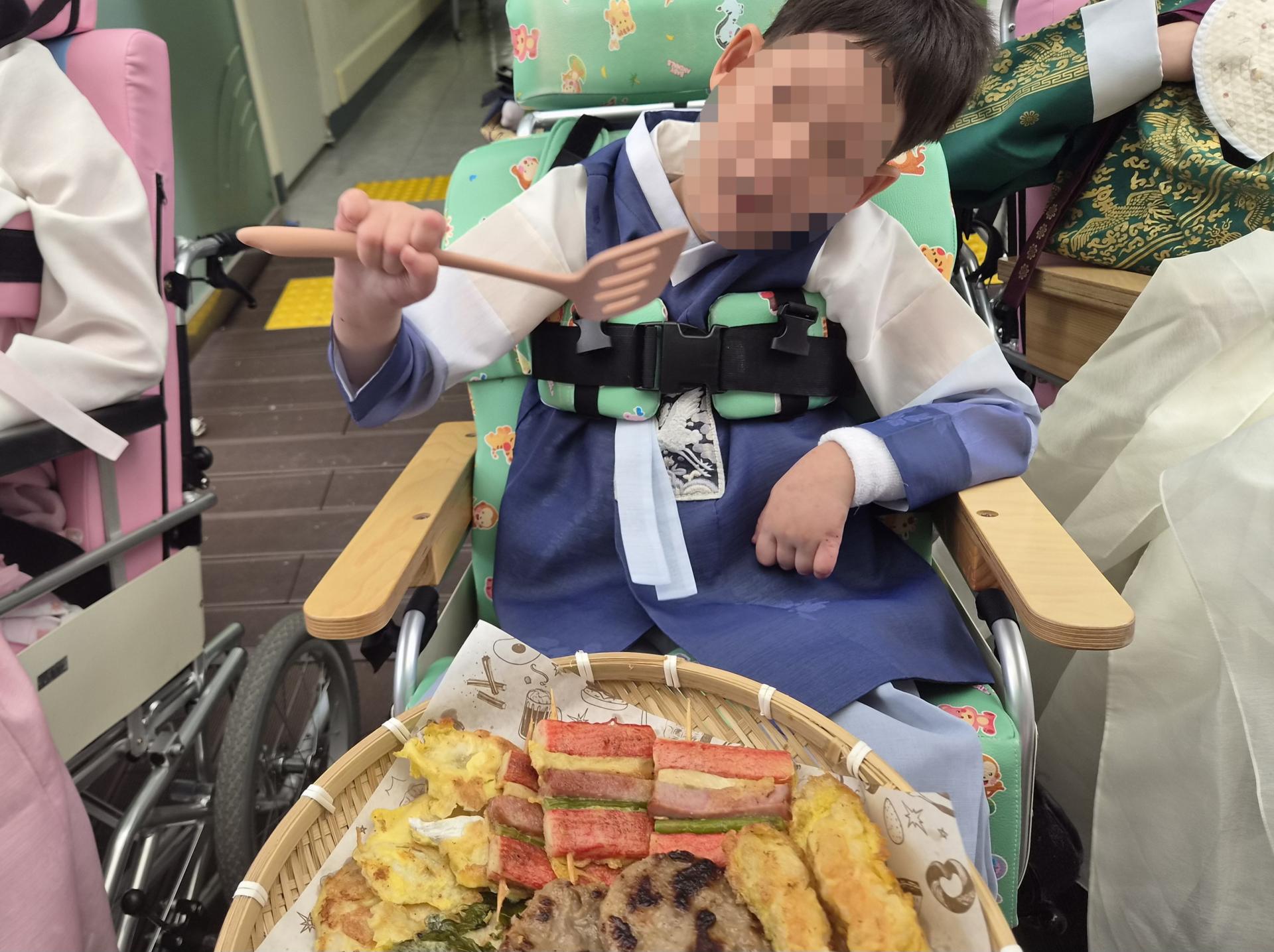 모듬전 앞에서 뒤집개를 들고 있는 이용자