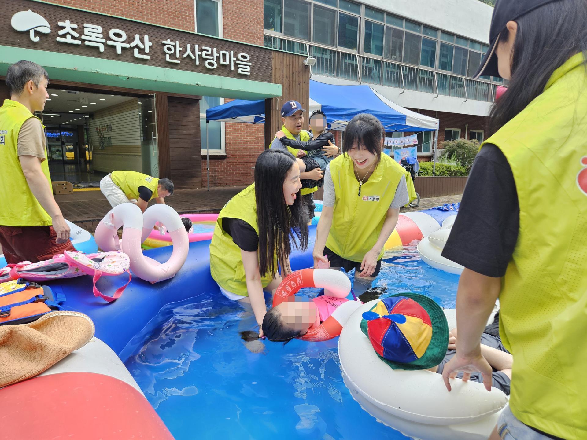 큰 풀장에서 물놀이를 하며 즐거워하는 이용자와 봉사자