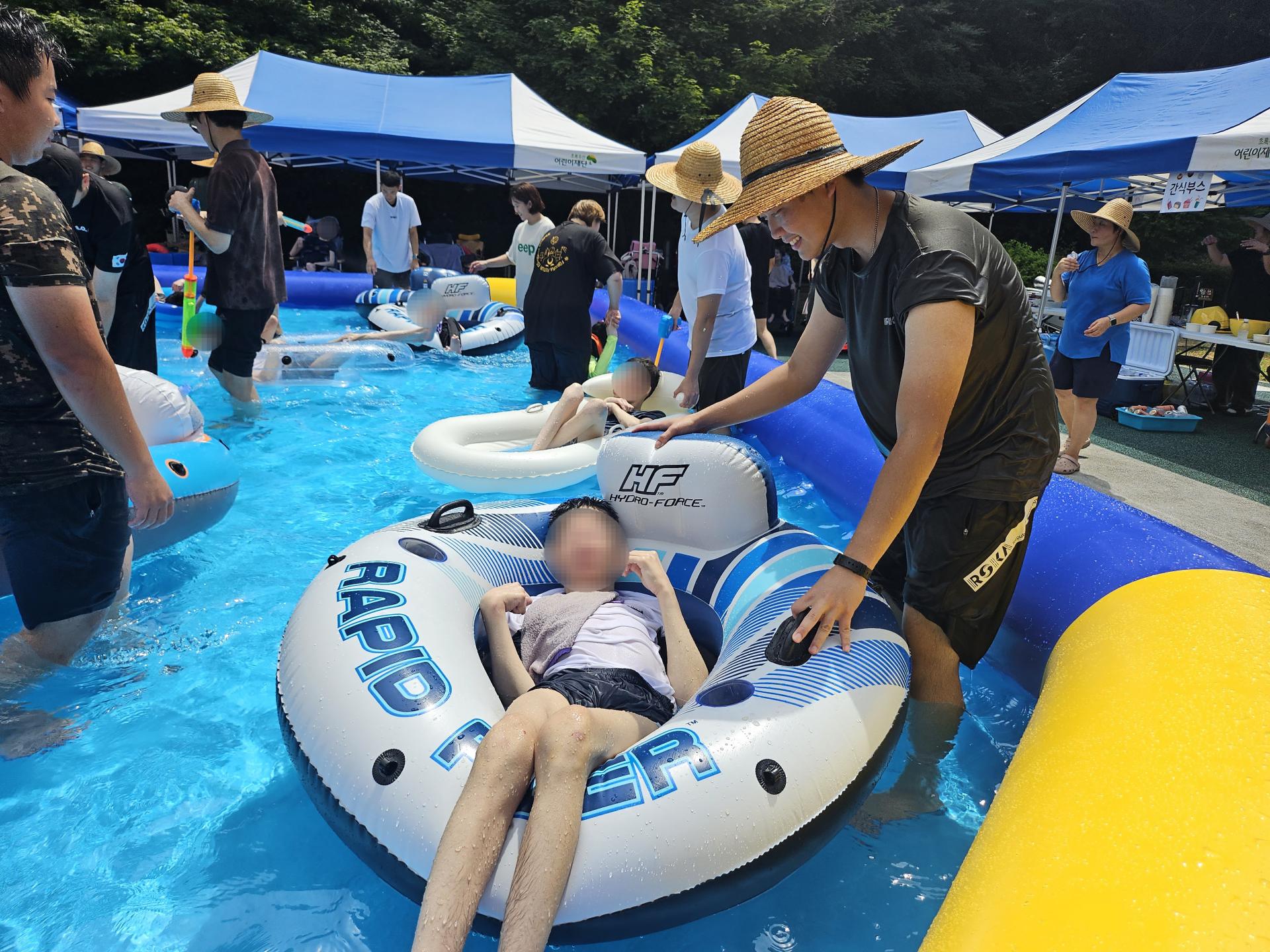 튜브를 탄 이용자가 물놀이를 즐길수 있게 함께하는 자원봉사자들