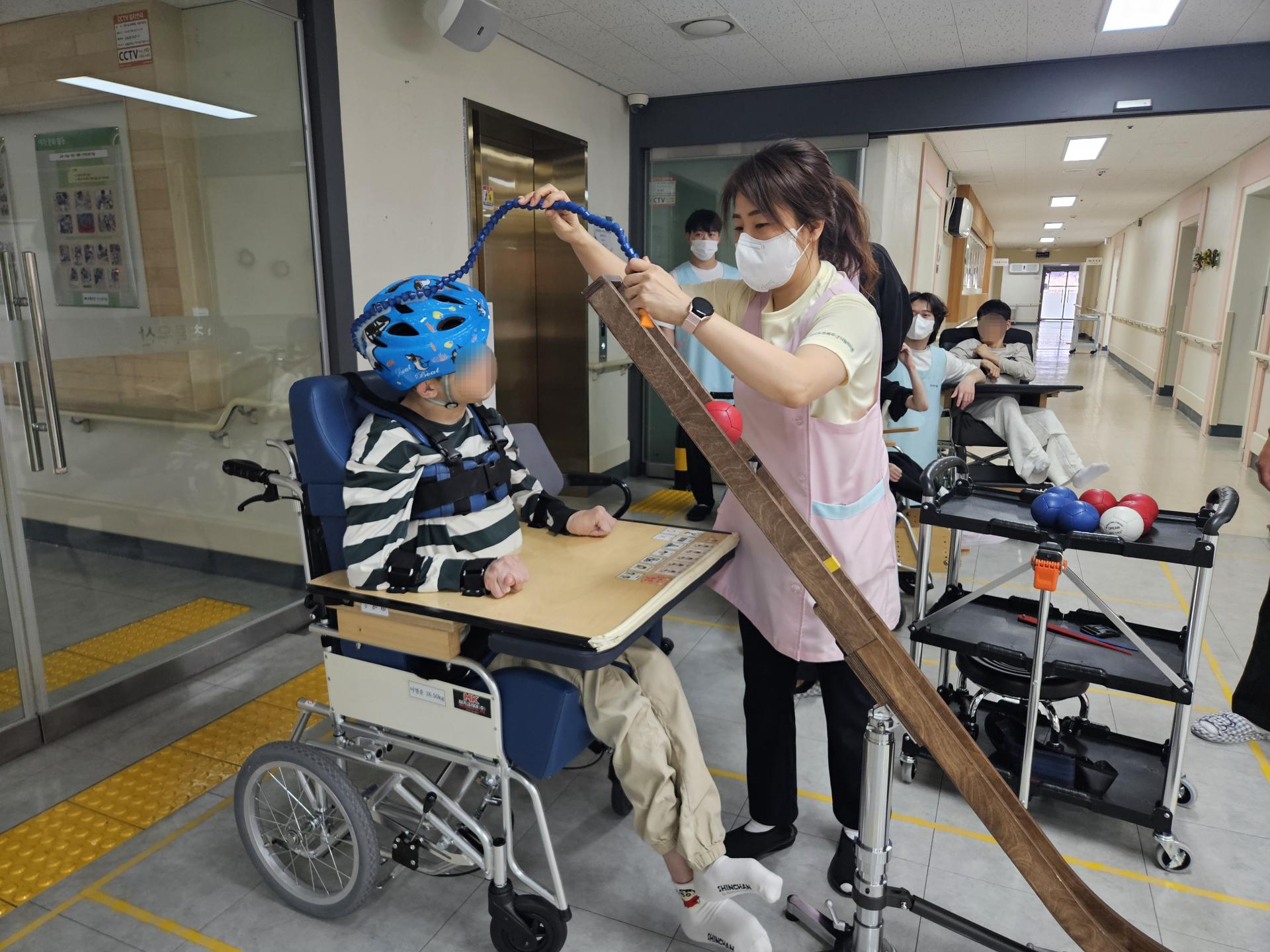 공 굴리기를 준비하는 이용자와 옆에서 지켜보는 이용자,직원들