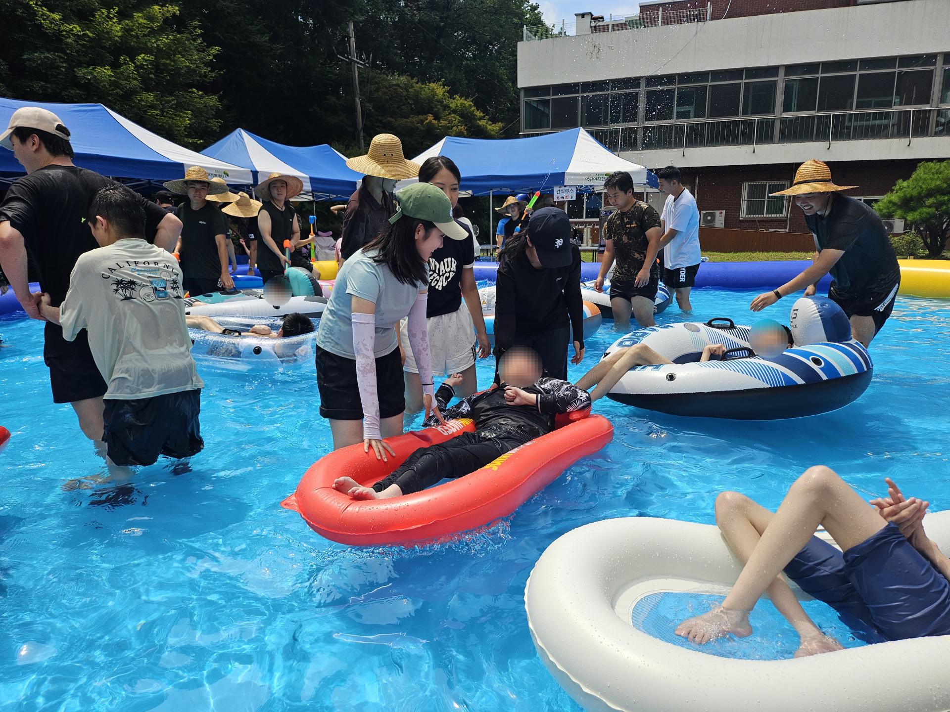 튜브를 탄 이용자가 물놀이를 즐길수 있게 함께하는 자원봉사자들