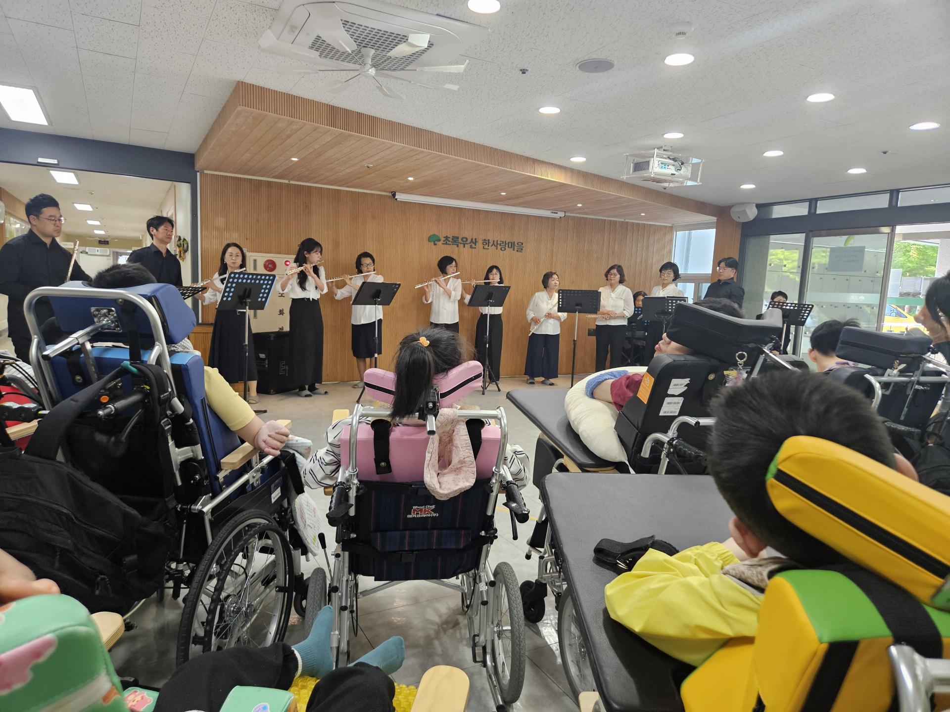플룻연주를 하고 있는 사랑의교회 단원들과 집중해서 듣고 있는 이용자들