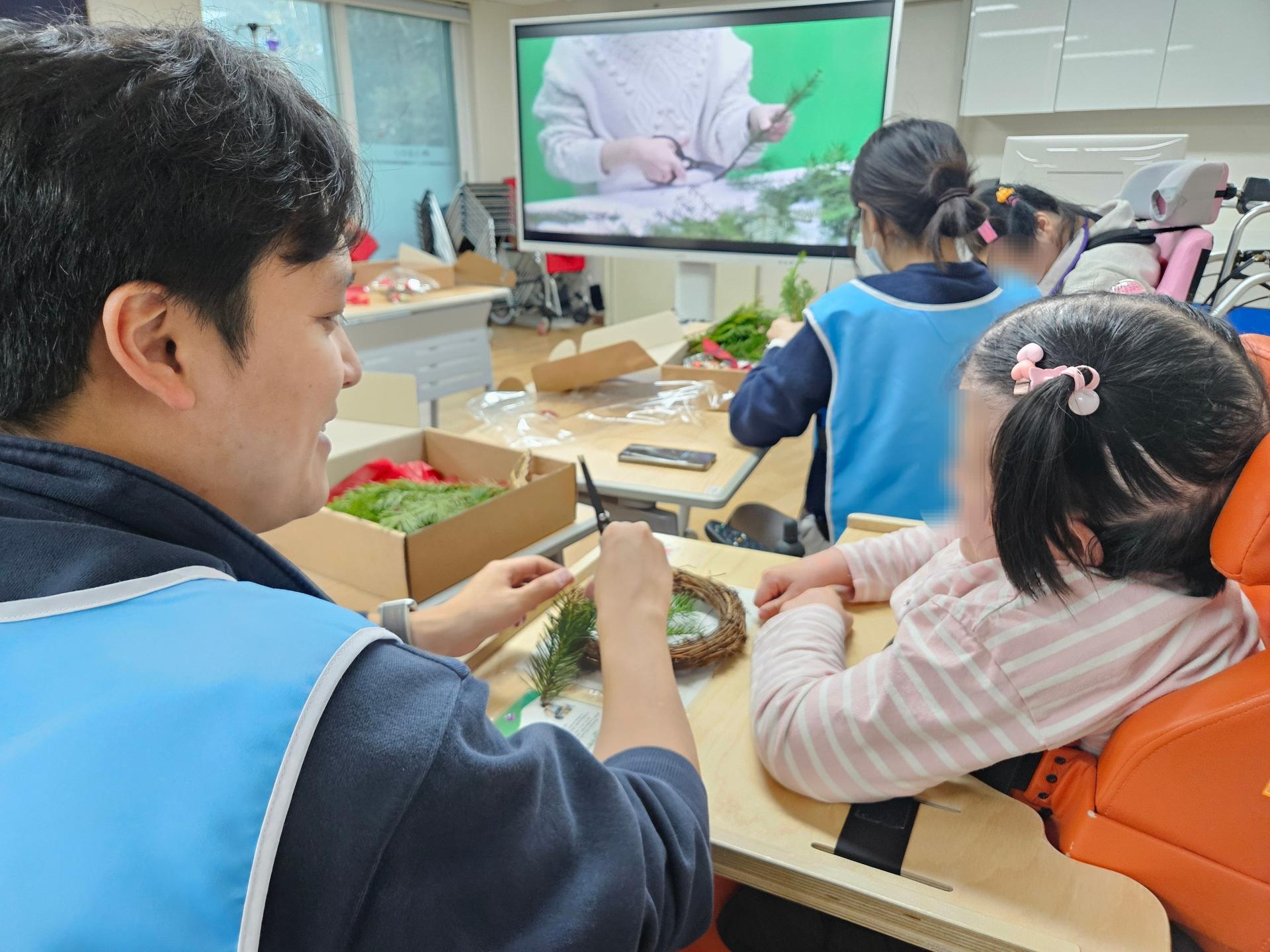 이용자와 함께 리스를 만드는 봉사자