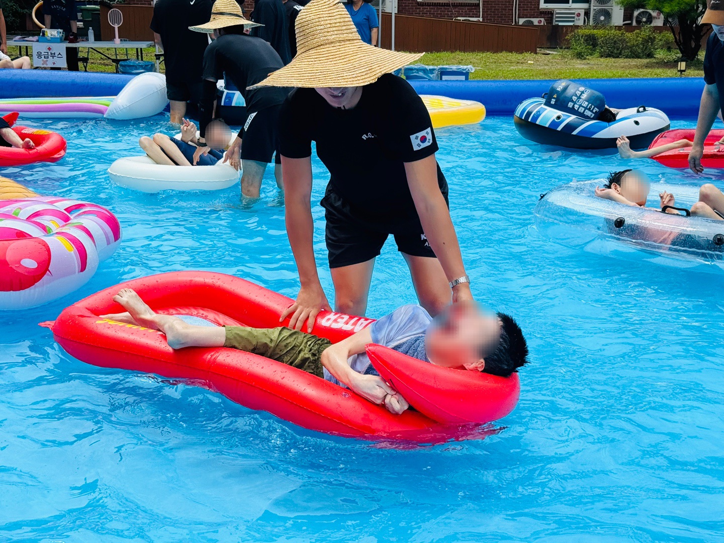 튜브위에서 즐거워하는 이용자와 잡아주는 자원봉사자