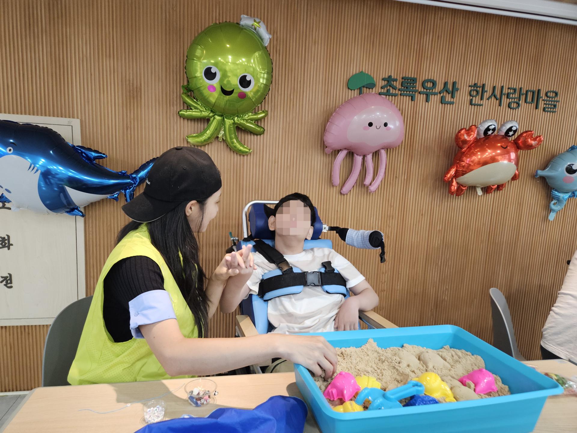노래놀이를 하며 촉감을 느껴보는 이용자와 봉사자