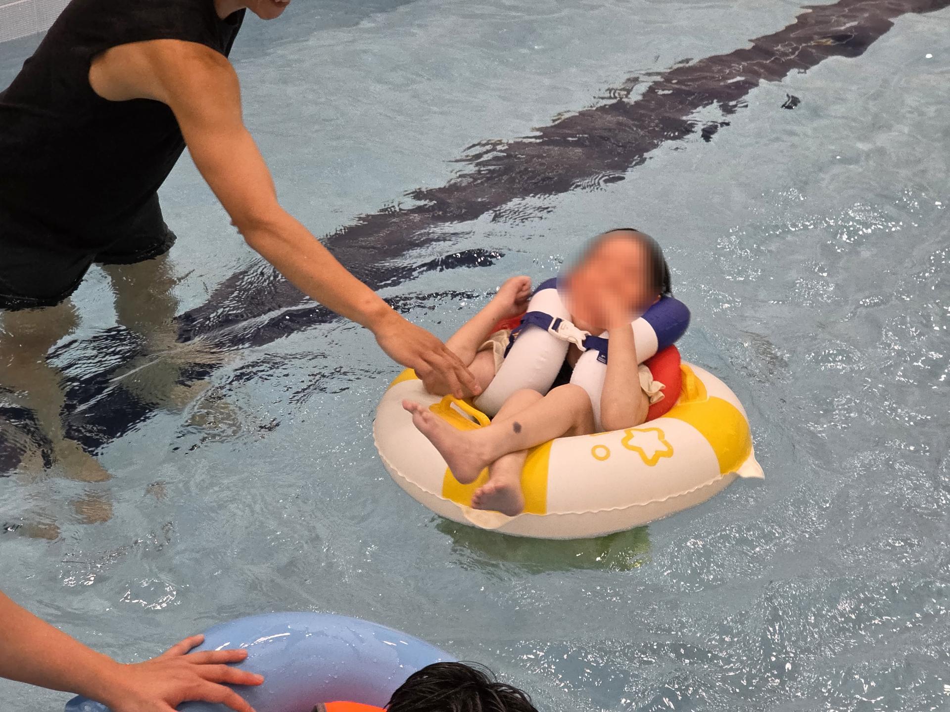 튜브와 구명조끼를 착용하고 물속에서 즐거워하는 이용자와 잡아주는 선생님