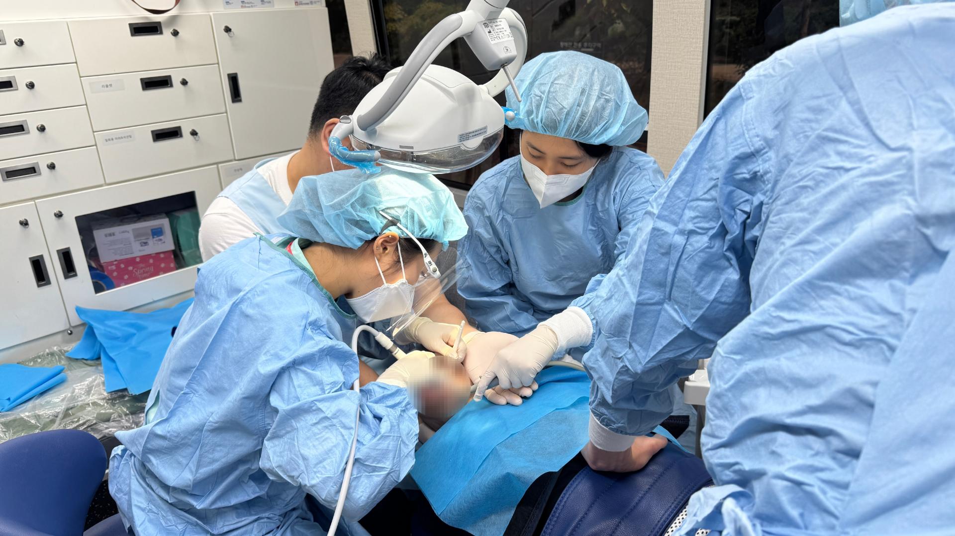 이동진료 차 안에서 스케일링을 받는 이용자와 진행하는 의료진들