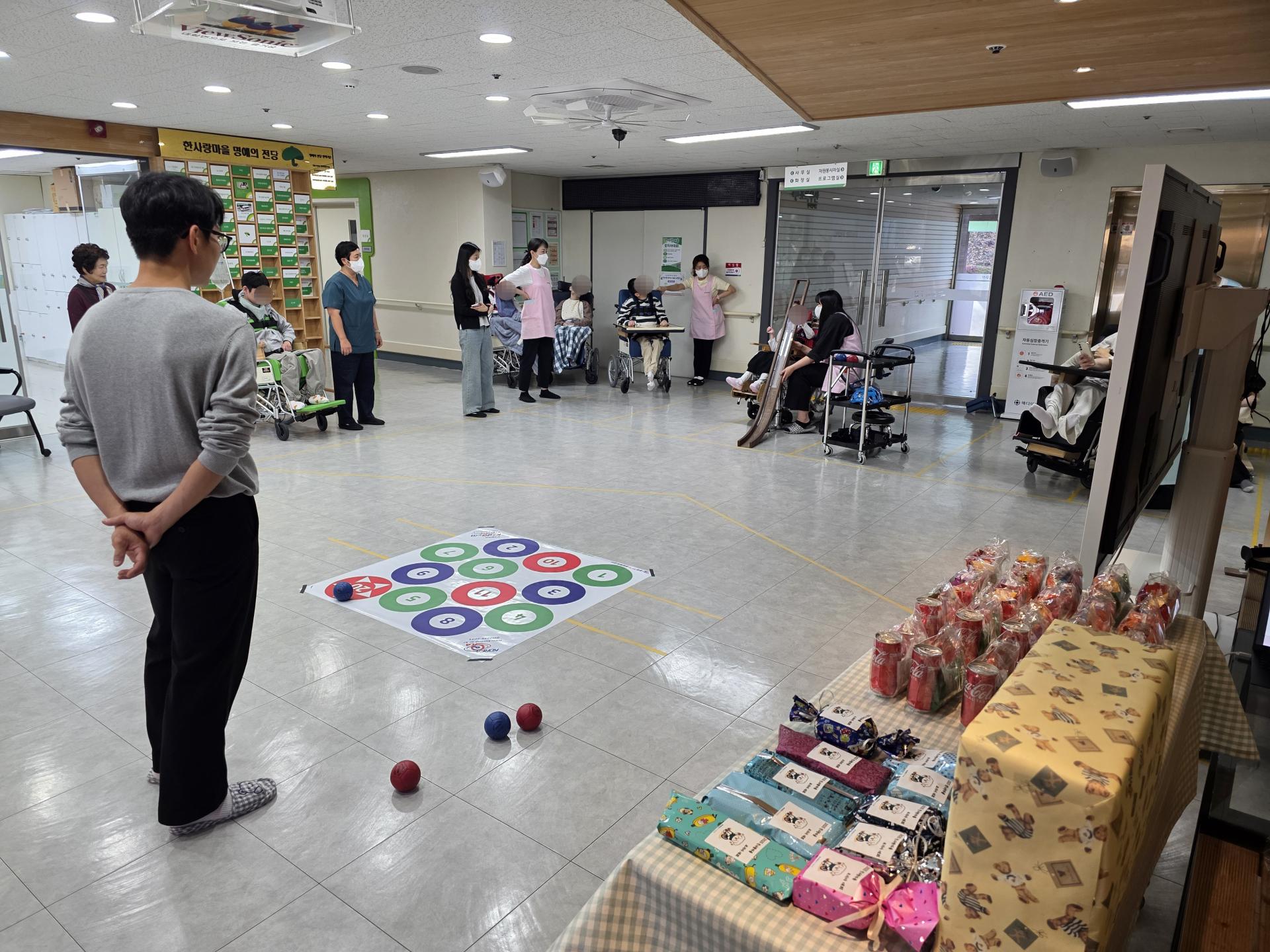 공 굴리기를 준비하는 이용자와 옆에서 지켜보는 이용자,직원들