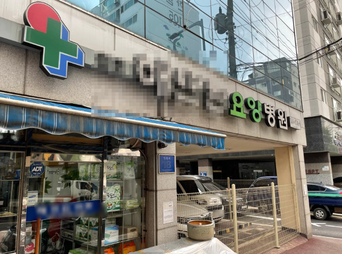 "수원시에 위치한 요양병원 건물 외관 전경, 1층에는 약국과 병원 입구가 함께 있으며 병원 간판과 출입구가 보이는 모습"
