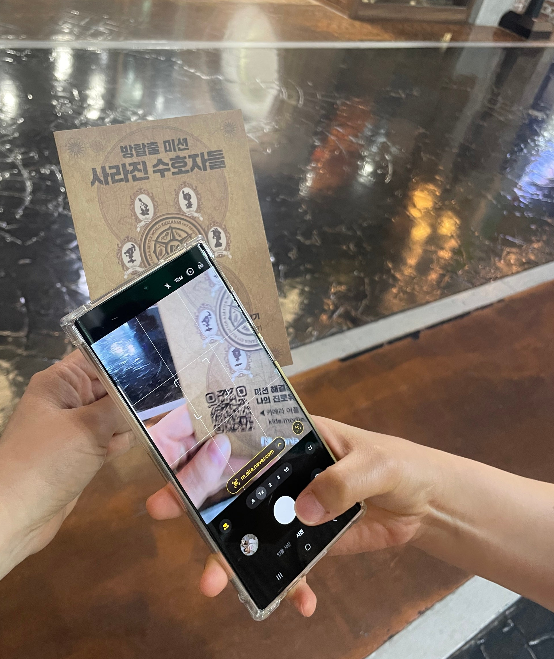 <img src="SE-2c182f64-ac9d-46a1-acec-094837102d2e.jpg" alt=“핸드폰으로 키자니아 모들 방탈출 큐알 찍는 장면”>