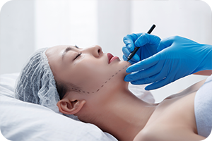 의사가 누워있는 환자의 턱선에 줄을 긋는다.