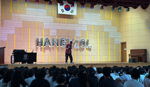학교 강당 무대에서 비트박스 공연 중인 비트박스 타조와 관람 중인 학생들