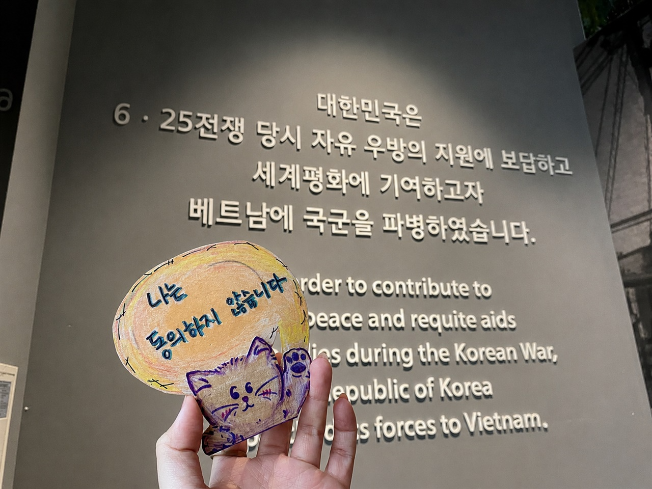 전쟁기념관 전시에 대한 항의 메시지를 담은 탄탄이의 피켓 액션. 피해생존자 응우옌티탄이 전쟁기념관에서 했던 말을 피켓에 적었다.