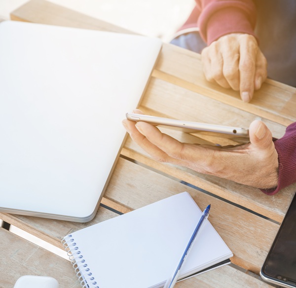 man-using-digital-tablet-with-laptop-spiral-notepad-pen-wooden-desk.jpg