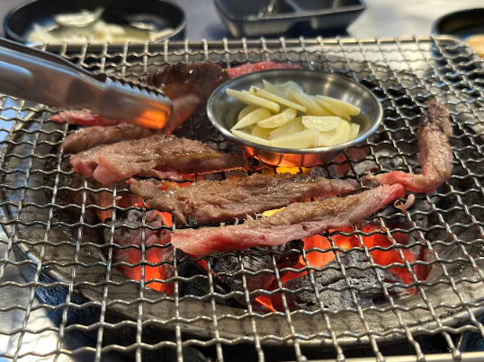 필리핀 마닐라 말라테 맛집 홍이 식당의 불판 위에서 구워지고 있는 고기와 마늘 골드바 에이전시