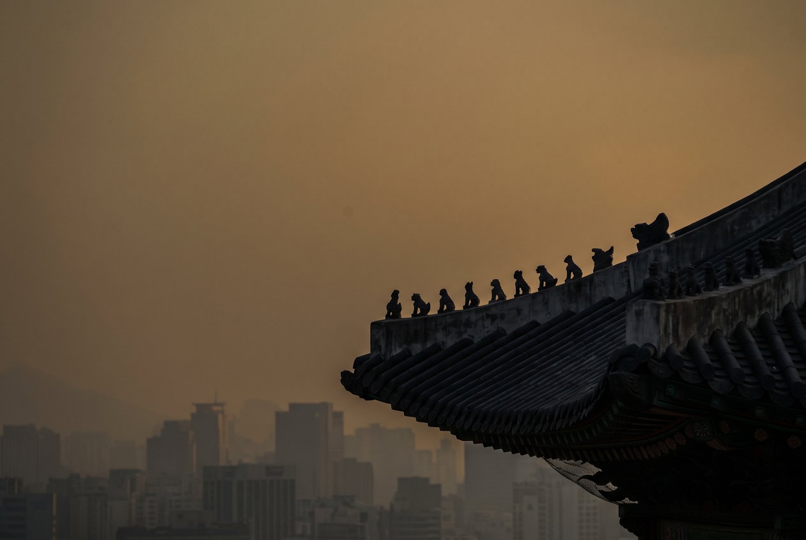 japsang figures on a Korean palace roofline against the Seoul skyline