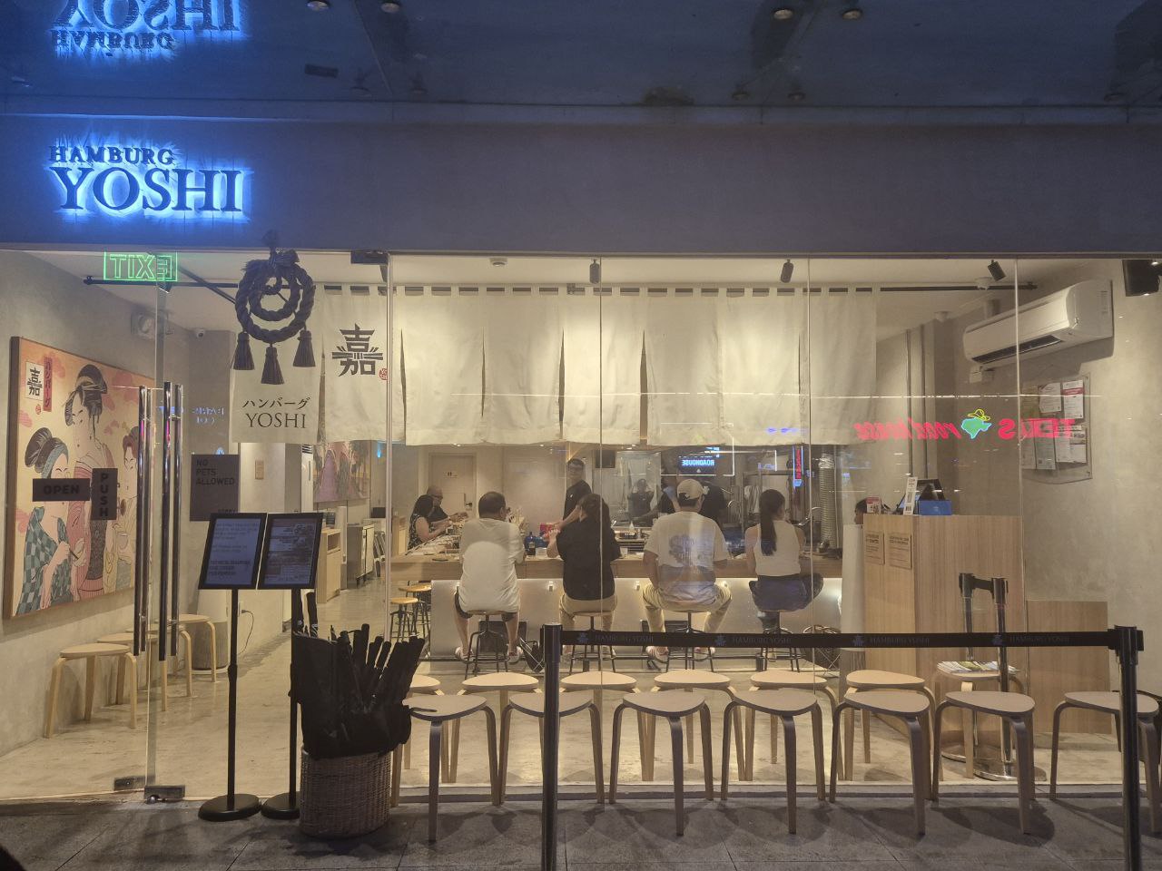 보니파시오 하이스트리트 사우스에 위치한 함버그 요시(Hamburg Yoshi)의 세련된 통유리 외관과 식사 중인 손님들