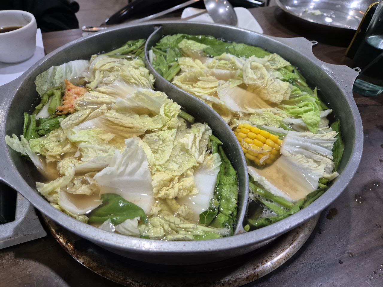 오카다 및 솔레어 근처 식당인 마카파칼 샤브칸의 반반 냄비에 신선한 배추와 옥수수 등 야채가 가득 담긴 샤브샤브 육수입니다.