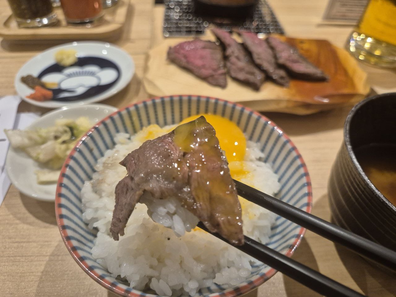 갓 지은 쌀밥 위에 신선한 날달걀 노른자와 전용 간장을 곁들여 고기와 함께 즐기는 한 입