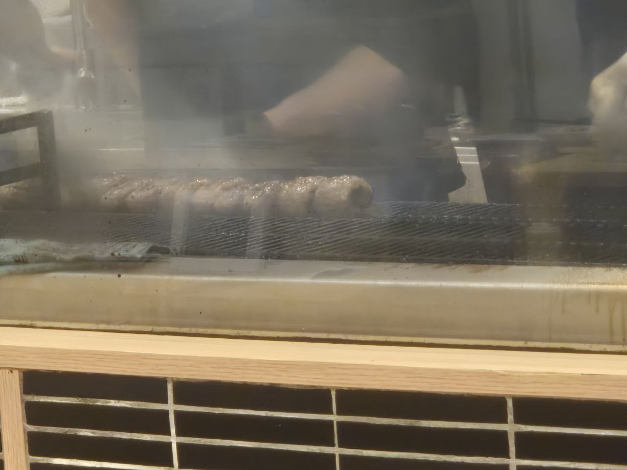 숯불 그릴 위에서 연기를 내며 구워지는 육즙 가득한 일본식 함바그 스테이크의 조리 모습