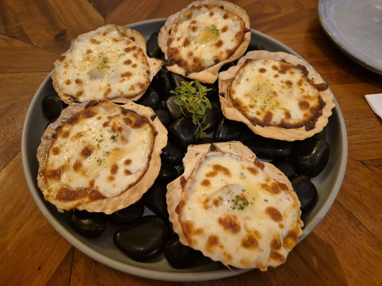 치즈와 특제 소스를 얹어 오븐에 구워낸 봄 고스토의 인기 에피타이저 오븐 베이크드 스캘럽