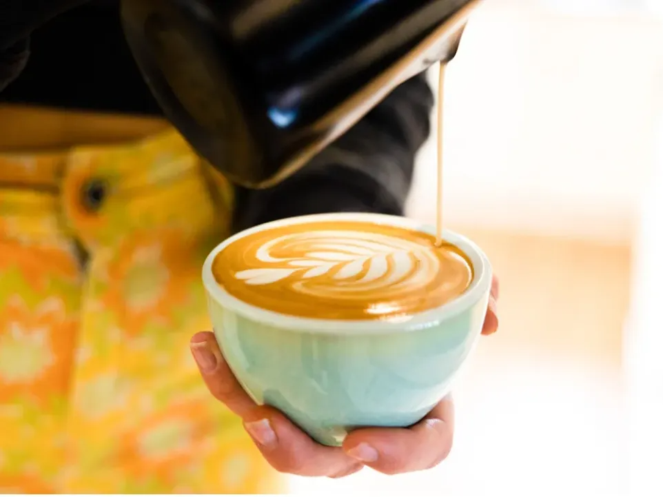 Fire and Flow Coffee의 바리스타가 우유 기반 음료를 제공하고 있습니다.