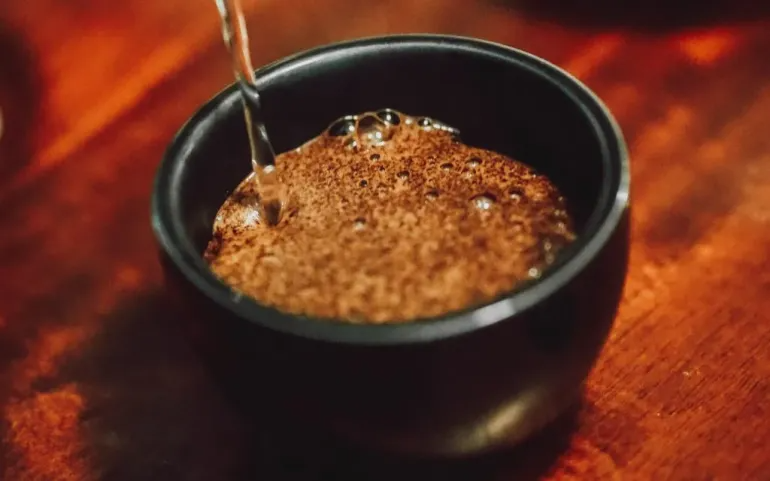 Water is poured into a cupping bowl for coffee sensory analysis.