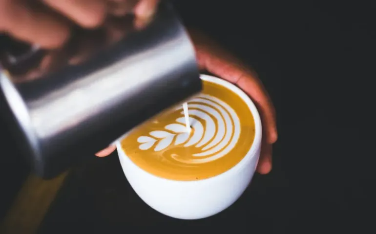A barista pours latte art with milk.