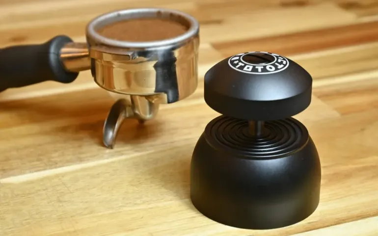 A coffee portafilter alongside a Weiss distribution tool.