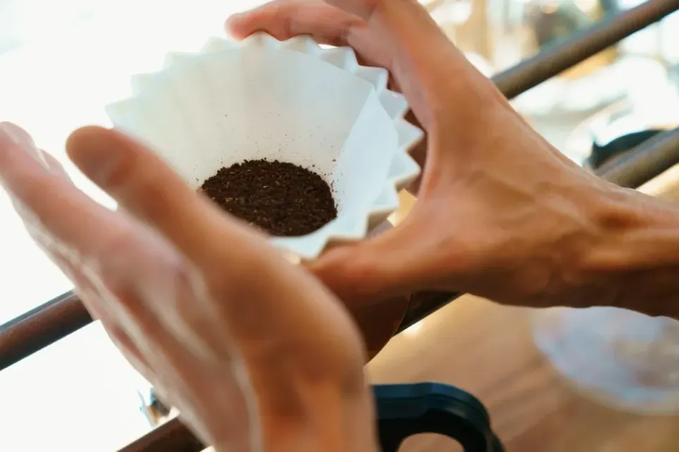 A barista settles coffee grounds in an Origami brewer.