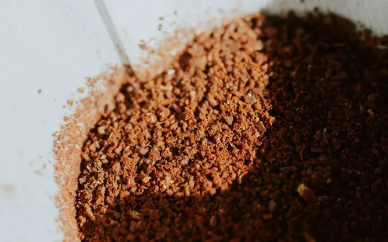 Coffee grounds sit inside a coffee filter paper within a pour over brewer.