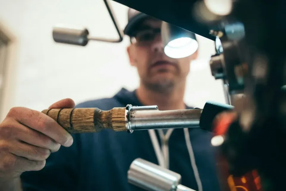 A roaster inspects coffee while it's being roasted.