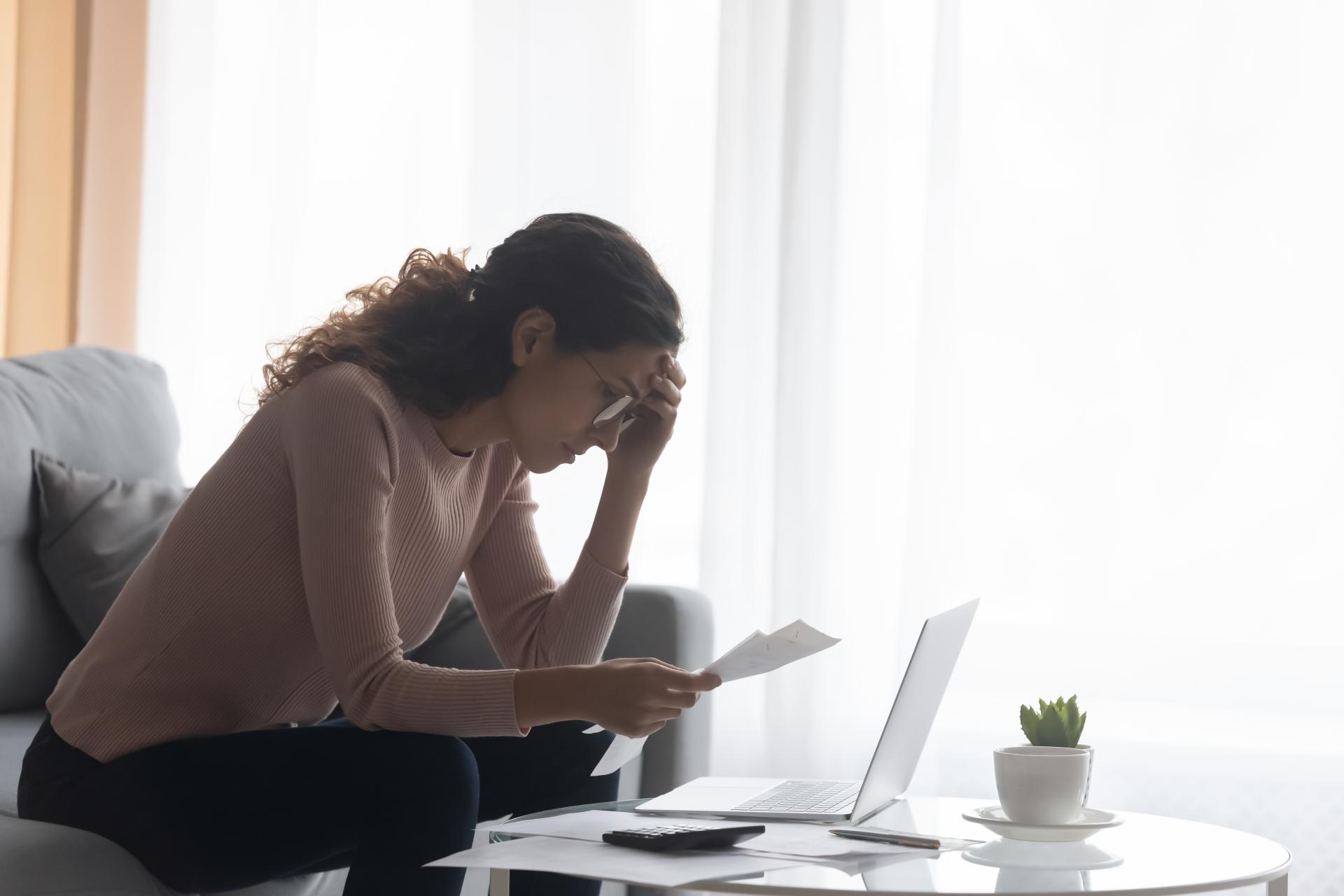 depressed-woman-wearing-glasses-calculating-bills-touching-forehead-looking-receipt-worried-about-financial-problem-lack-money-debt-bankruptcy-sitting-couch-table-with-laptop.jpg