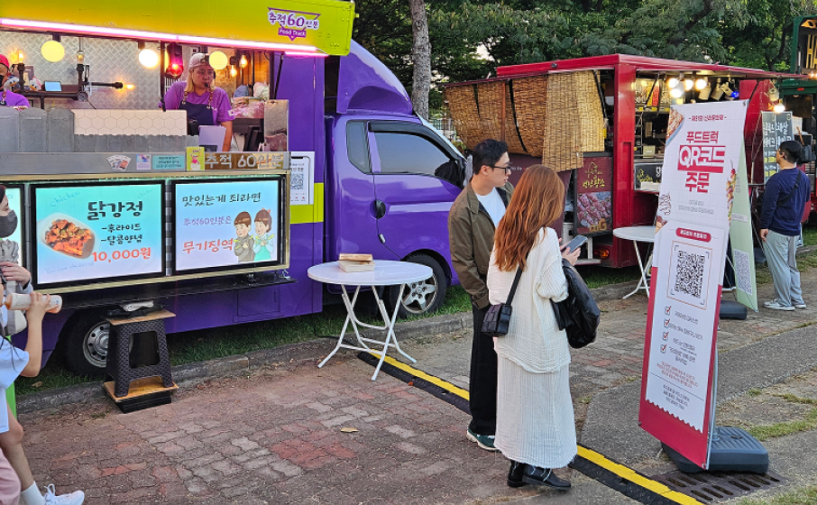 푸드트럭 앞에 배치된 메이트 행사결제솔루션 QR코드로 주문하는 손님들